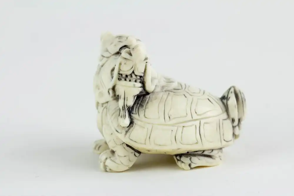 Figur, China, 19./20. Jh., Bixie (eine Figur der chinesischen Mythologie, ein Wesen mit dem Körper einer Schildkröte und dem Kopf eines Drachen), Elfenbein, geschnitzt und geschwärzt. L: 4 cm. 1