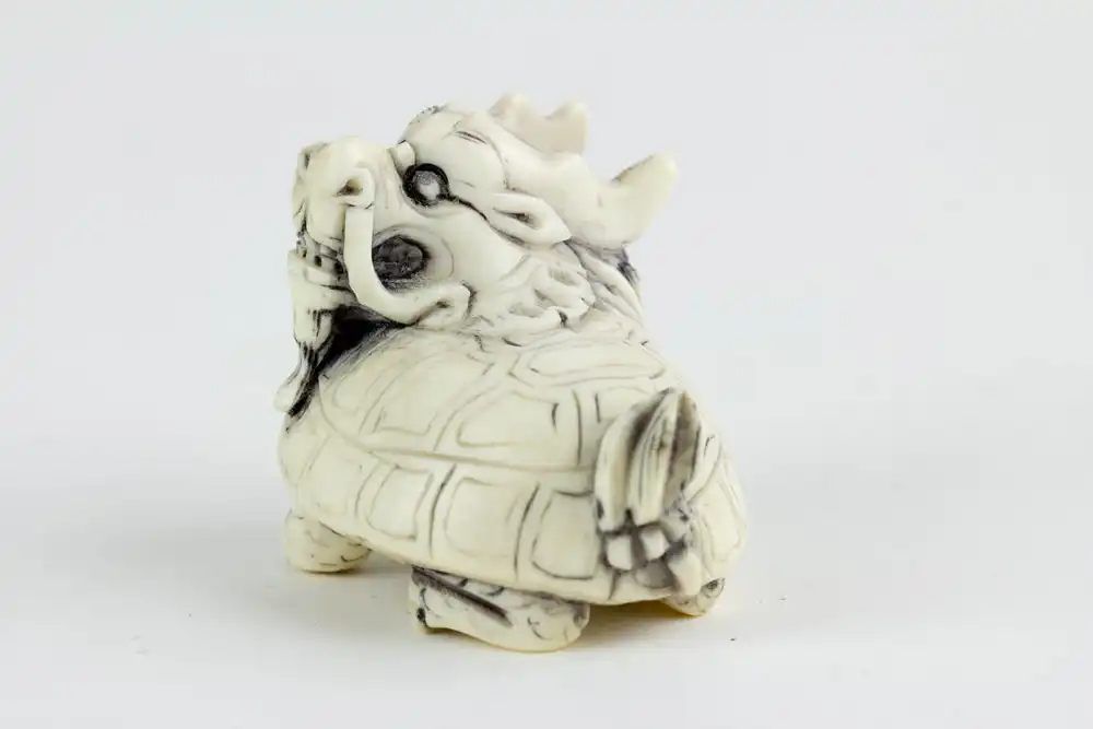 Figur, China, 19./20. Jh., Bixie (eine Figur der chinesischen Mythologie, ein Wesen mit dem Körper einer Schildkröte und dem Kopf eines Drachen), Elfenbein, geschnitzt und geschwärzt. L: 4 cm. 4