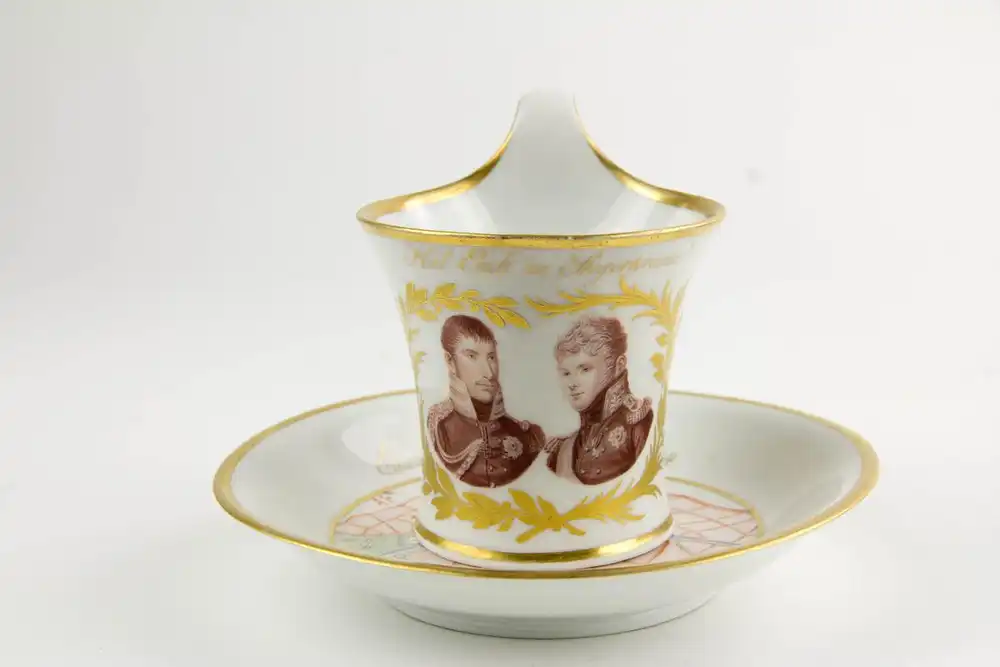 Tasse und Untertasse, gemarkt KPM, 1814, Kalathos-Form, bemalt und Umdruckdekor, auf Schauseite Portrait von König Friedrich Wilhelm III und Zar Alexander I, umgeben von Lorbeerkranz in Gold, Umschrift: Heil Euch im Siegerkranz, Untertasse mit... 0