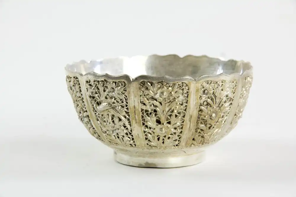 Zierschale, China, erste Hälfte 20. Jh., Silberbronze versilbert, in umlaufenden Kartuschen plastisch aufgelegte Vögel und Blumen, geschwungener Rand, kurzer Standring, feine Qualität, Gebrauchsspuren, fleckig. D: 12,5 cm, H: 6,5 cm. 1