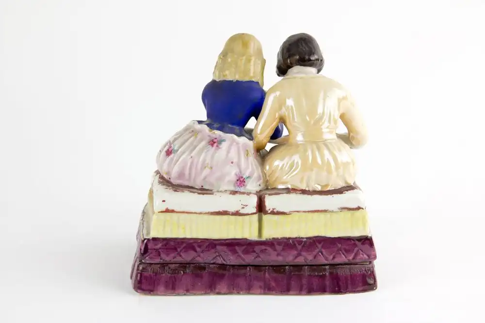 Schreibtischgarnitur, Thüringen, Mitte 19. Jh., ungemarkt, polychrom bemalt, in Form von 2 sitzenden Kindern, ein Schulbuch lesend, im inneren 2 Gefäße mit Masken aufgelegt für Tinte und Sand, stärkerer Farbabrieb, Gebrauchsspuren. H: 15 cm, B:... 2