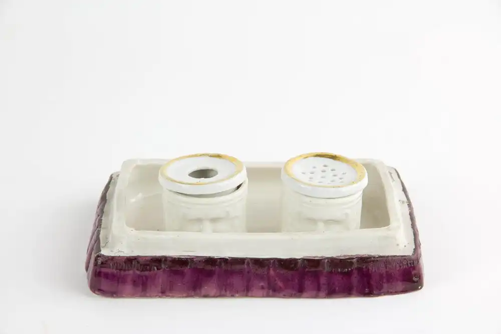 Schreibtischgarnitur, Thüringen, Mitte 19. Jh., ungemarkt, polychrom bemalt, in Form von 2 sitzenden Kindern, ein Schulbuch lesend, im inneren 2 Gefäße mit Masken aufgelegt für Tinte und Sand, stärkerer Farbabrieb, Gebrauchsspuren. H: 15 cm, B:... 3