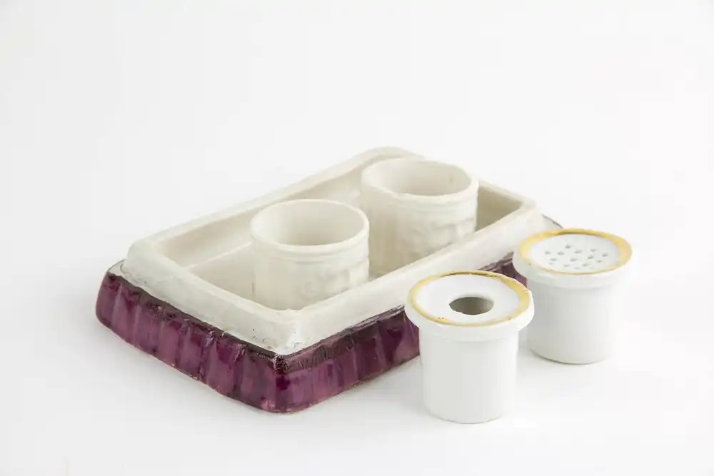 Schreibtischgarnitur, Thüringen, Mitte 19. Jh., ungemarkt, polychrom bemalt, in Form von 2 sitzenden Kindern, ein Schulbuch lesend, im inneren 2 Gefäße mit Masken aufgelegt für Tinte und Sand, stärkerer Farbabrieb, Gebrauchsspuren. H: 15 cm, B:... 4