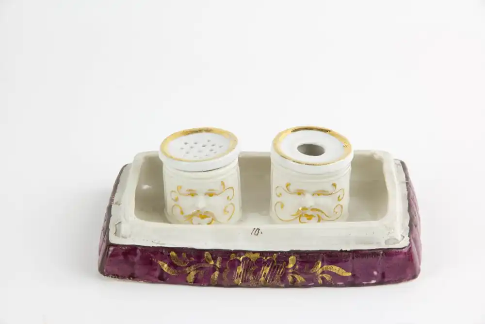 Schreibtischgarnitur, Thüringen, Mitte 19. Jh., ungemarkt, polychrom bemalt, in Form von 2 sitzenden Kindern, ein Schulbuch lesend, im inneren 2 Gefäße mit Masken aufgelegt für Tinte und Sand, stärkerer Farbabrieb, Gebrauchsspuren. H: 15 cm, B:... 5