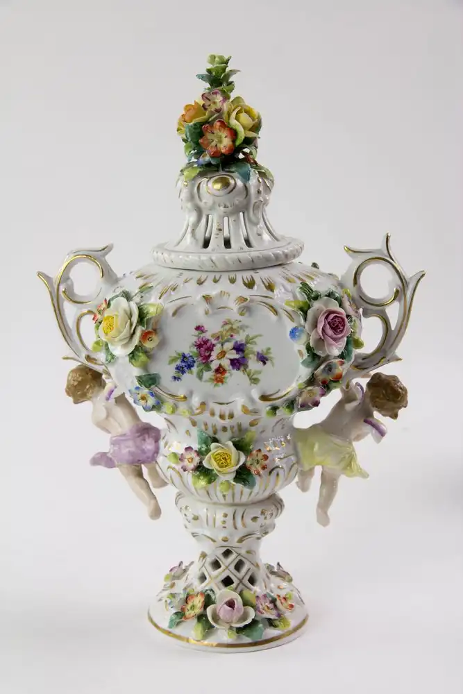 Kleine Duftvase, Mitte 20. Jh., Bindeschild Marke Thüringen, reichlich goldverziertes Gefäß mit Henkeln und Deckeln, mit plastisch aufgelegten Blüten und Puttis, stärker bestoßen, H: 29 cm. 2