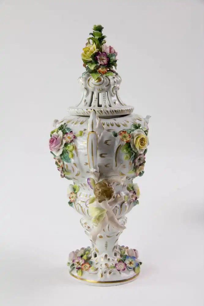 Kleine Duftvase, Mitte 20. Jh., Bindeschild Marke Thüringen, reichlich goldverziertes Gefäß mit Henkeln und Deckeln, mit plastisch aufgelegten Blüten und Puttis, stärker bestoßen, H: 29 cm. 3