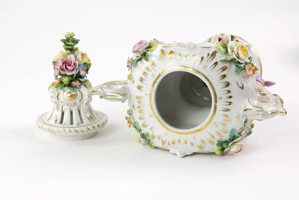 Kleine Duftvase, Mitte 20. Jh., Bindeschild Marke Thüringen, reichlich goldverziertes Gefäß mit Henkeln und Deckeln, mit plastisch aufgelegten Blüten und Puttis, stärker bestoßen, H: 29 cm. 4