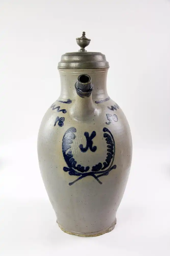 Tüllenkanne, Altenburg, graues Steinzeug, mit Blaumalerei, verziert mit K in stilisierten Palmwedelkreis und 1850, Zinndeckel, unbeschädigt, Stand mit starken Abplatzern, H: 44 cm. 0