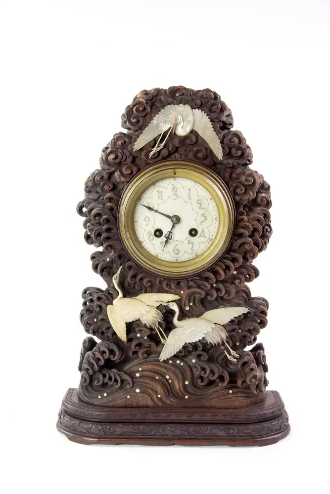 Seltene Uhr, Japan, um 1880, mit französischem Uhrwerk, Holzgehäuse fein geschnitzt mit Wellen und Wolken, verziert mit aufgelegten kleinen Permuttkreisen und drei fein geschnitzten Kranichen aus Perlmutt, sehr guter Zustand, ein Kranich... 0
