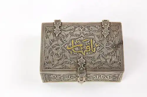 Schatulle, Arabisch, um 1900, Silber, Goldeinlagen, mit floralen Motiven graviert, auf Deckel Schriftzeichen, innen mit Holz ausgeschlagen, Gebrauchsspuren. B: 9,2 cm, H: 3 cm, T: 6 cm.