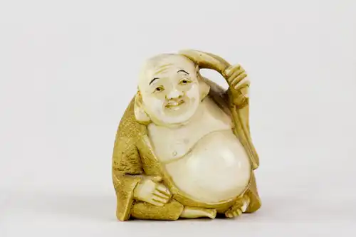 Netsuke, Japan, Meiji-Zeit, um 1900, Elfenbein Buddha mit Palmwedel, fein geschnitzt und signiert, Gebrauchsspuren. H: 3,5 cm.