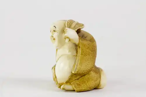 Netsuke, Japan, Meiji-Zeit, um 1900, Elfenbein Buddha mit Palmwedel, fein geschnitzt und signiert, Gebrauchsspuren. H: 3,5 cm.