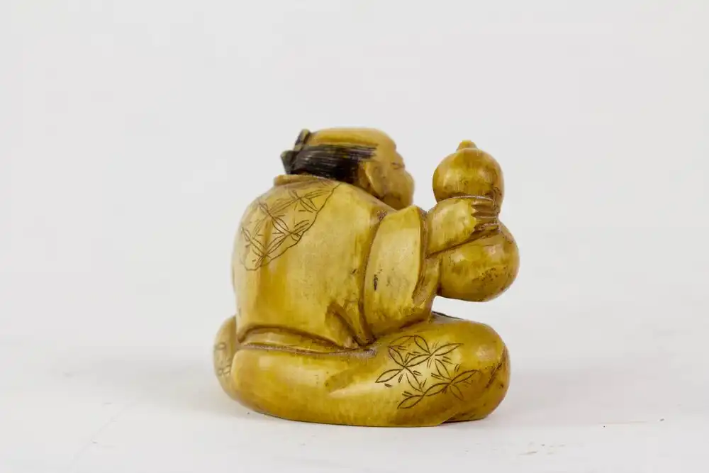 Netsuke, Japan, Meiji Zeit, um 1900, signiert, Elfenbein, sitzender Mann mit Flaschenkürbis und Schale, Gebrauchsspuren. H: 3,5 cm. 1