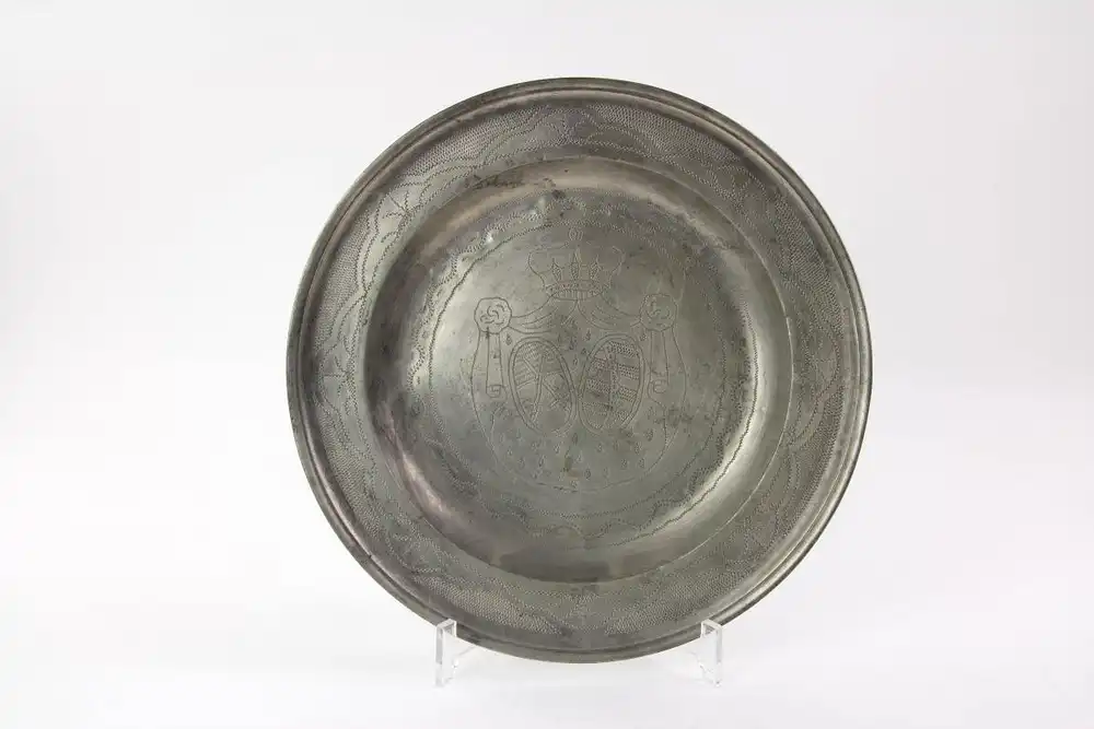 Teller, 18. Jh., Zinn, im Fond Kursächsisches Wappen graviert, Fahne mit geometrischen Ornamenten verziert, Gebrauchsspuren. D: 29 cm. 0