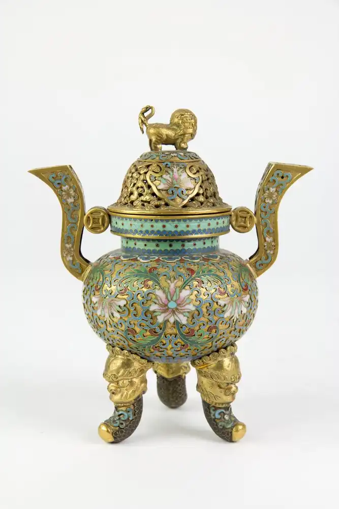 Räuchergefäß, China, 19./20. Jh.,  vergoldetes, durchbrochen gearbeitetes  Messinggefäß, verziert mit Blumen und Ornamenten in Cloisonné - Technik, auf drei mit Fabelwesen verzierten Füßen, 2 gebogene Henkel mit Keschmünzen, Deckel mit Fo... 0