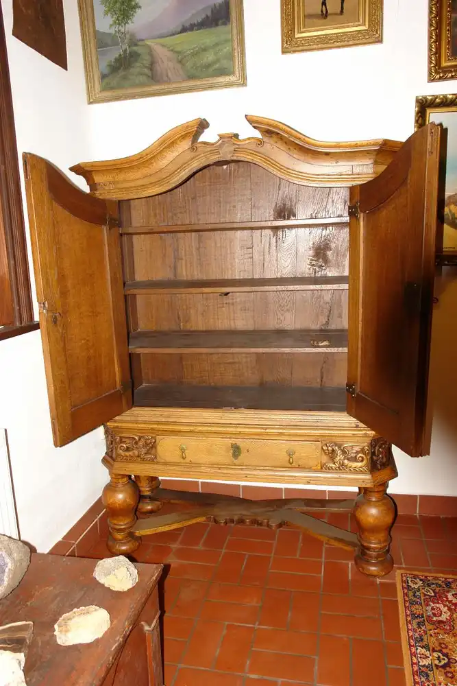 Stollenschrank, Barock, 2. Hälfte 18. Jh., norddeutsch, Eiche massiv, Korpus auf gedrechselten Säulen mit geschwungener Kreuzverstrebung, zweitürig, darunter zentrales Schubfach, Schubfach flankiert von zwei geschnitzten, geflügelten Löwen, neben... 3