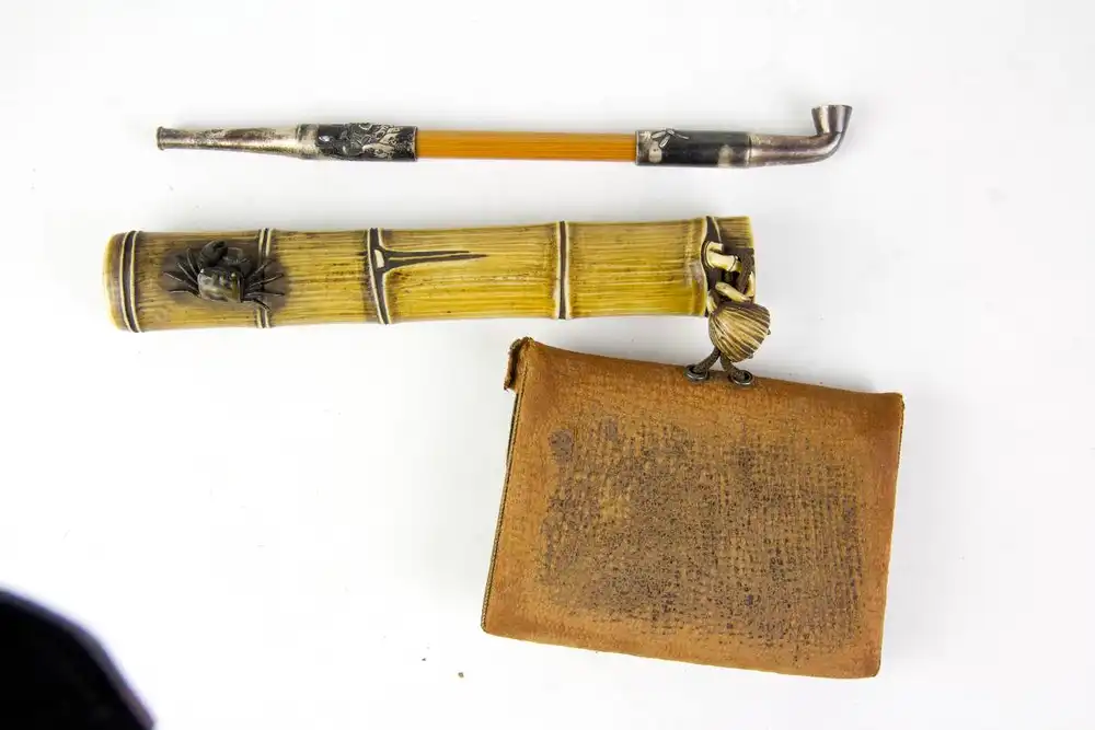 Rauchgarnitur, Japan, Meiji Zeit, bestehend aus Pfeife, Pfeifenbehälter und Tabakbeutel, Pfeife aus Silber, mit Blumen verziert, Mittelstück aus Bambus, geschnitzter Pfeifenbehälter aus Horn in Form eines Bambushalmes, verziert mit kleiner,... 1
