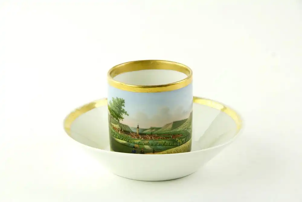 Tasse und Untertasse, um 1820, Biedermeier, ungemarkt, zylindrische Form, bemalt mit einer Stadtansicht von Jena, feine Malerei, am Lippenrand restauriert, sonst unbeschädigt. H: 6 cm. 0