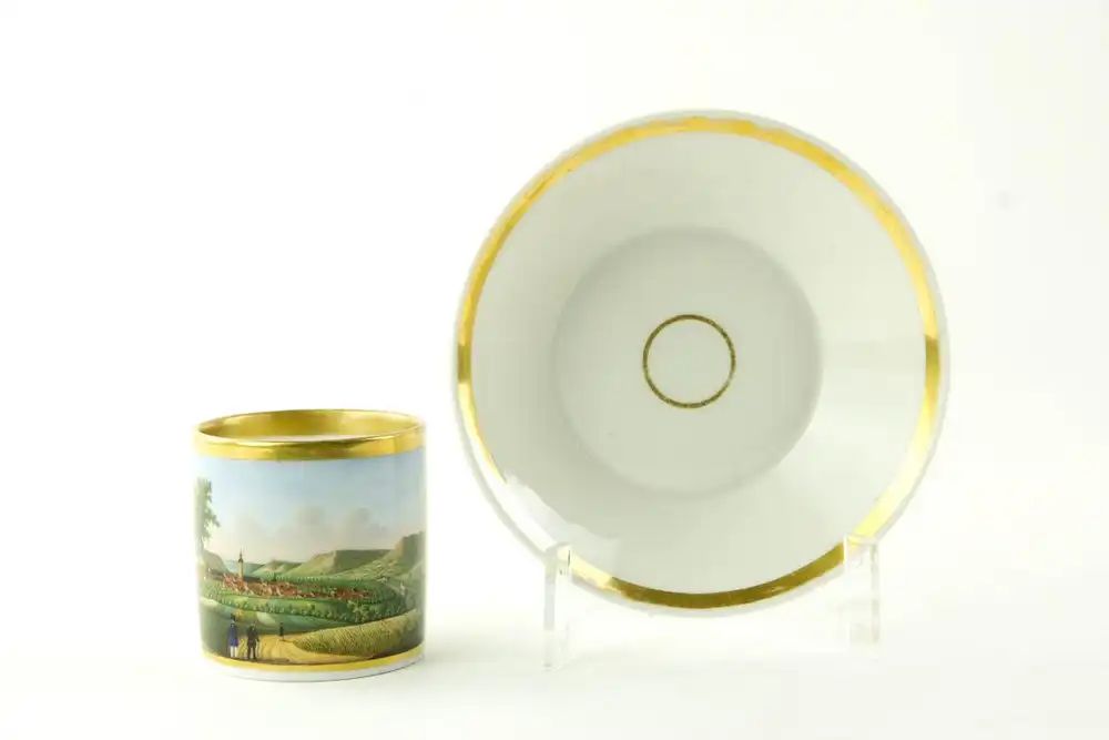 Tasse und Untertasse, um 1820, Biedermeier, ungemarkt, zylindrische Form, bemalt mit einer Stadtansicht von Jena, feine Malerei, am Lippenrand restauriert, sonst unbeschädigt. H: 6 cm. 1