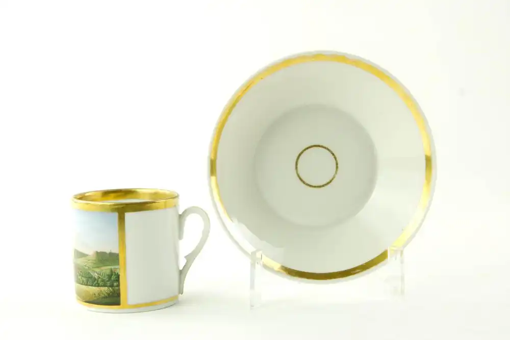 Tasse und Untertasse, um 1820, Biedermeier, ungemarkt, zylindrische Form, bemalt mit einer Stadtansicht von Jena, feine Malerei, am Lippenrand restauriert, sonst unbeschädigt. H: 6 cm. 2