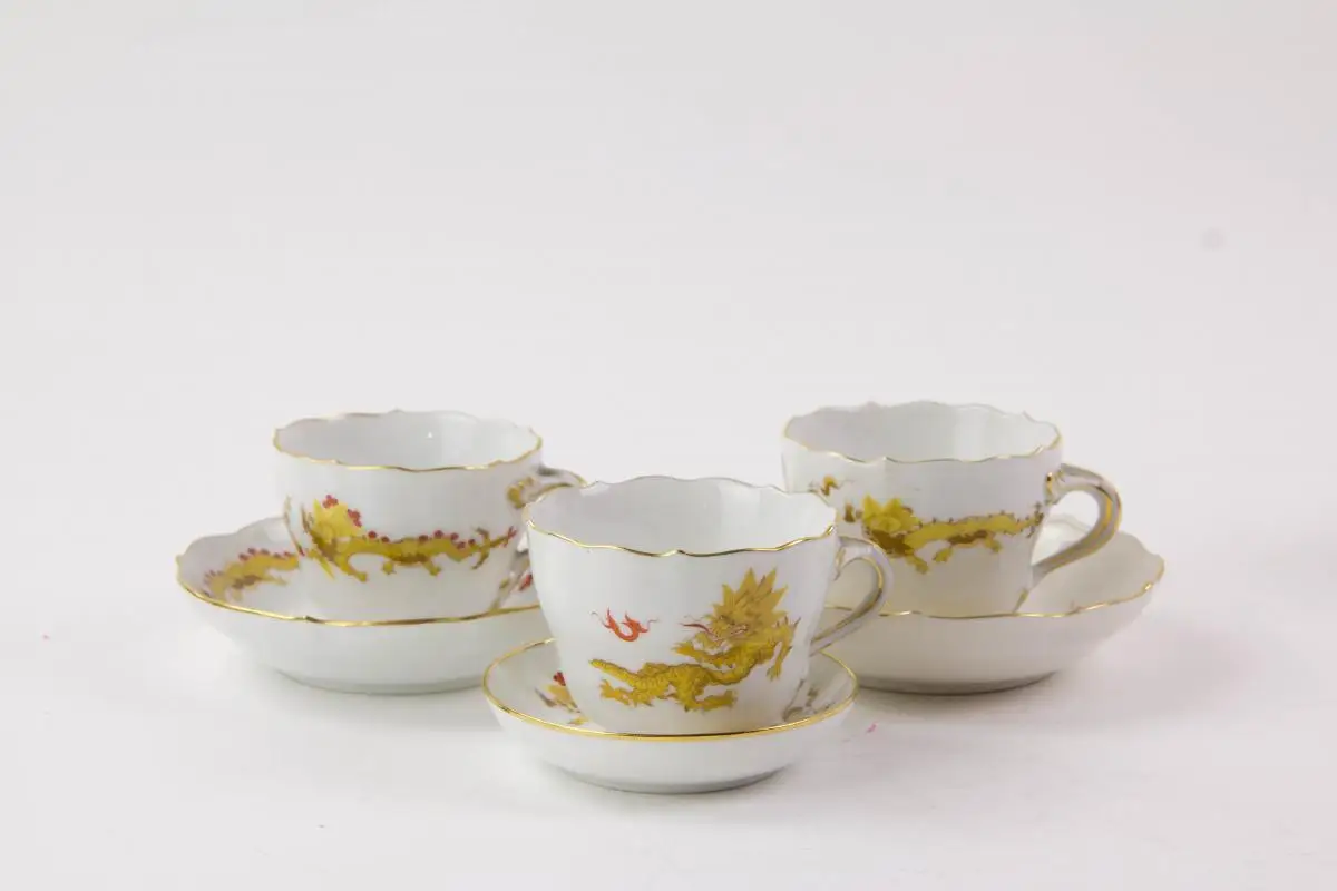 Konvolut Meißner Porzellan, gemarkt Meißen, verschiedene Schwertermarken, 1. Wahl, meist 20er Jahre, gelber Hofdrache, bestehend aus Teller, 3 Moccatassen und Vase, unbeschädigt. Teller D: 25 cm, Moccatassen H: 6 cm, Vase H: 10 cm. 3