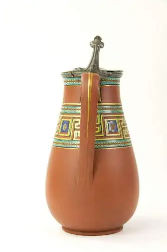 Birnkrug, um 1900, gemarkt Atkin Brothers, Sheffield, rote Keramik, umlaufend polychrome und goldene Bemalung im griechischen, antiken Stil, mit Zinndeckel, dieser defekt, Gebrauchsspuren. H: 22 cm.