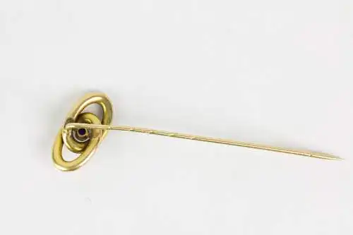 Krawattennadel, Anf. 20. Jh., gemarkt, 585er Gelbgold, zwei verschlungene Ringe, in der Mitte im Cabochon-Schliff gefasster Saphir, Gebrauchsspuren. L: 6,4 cm, 2,0 g.