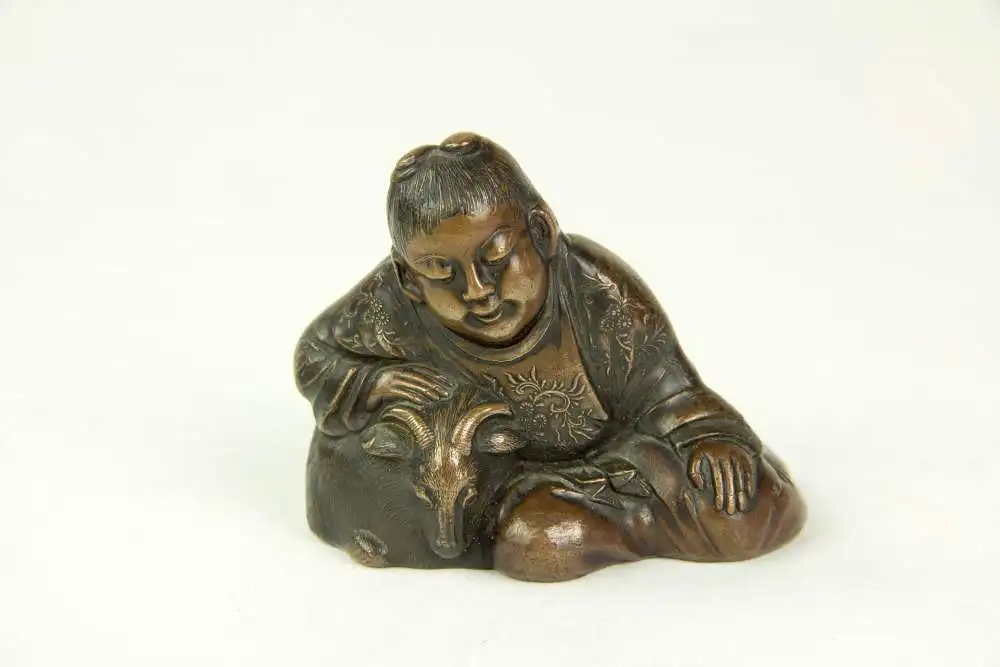 Figur, Japan, 19./20. Jh., Bronze, OKIMONO (jap. 置物, wörtlich: „Hinstellding“, typisch japanische Kunstschnitzarbeiten aus der Zeit der Meiji-Periode), Kind, das Zeige streichelt, Gebrauchsspuren, H: 5 cm. 0