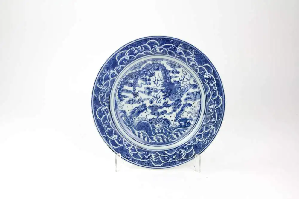 Teller,  China, 19./20. Jh., ungemarkt, im Spiegel mit zwei Drachen in Blaumalerei verziert, Fahne mit Wellen bemalt, leichte Gebrauchsspuren, unbeschädigt, D: 23 cm. 0