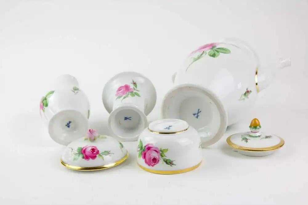 Service, 2. Hälfte 19. Jh., gemarkt Meißen, mit Rosen bemalt, goldverziert, Tassen mit bauchiger Form und hochgezogenem Henkel mit Schwanenkopf, 6-teilig, Kaffeekanne, Sahnekännchen, Zuckerdose mit Rosenknospe als Knauf, Vase, unbeschädigt. 7