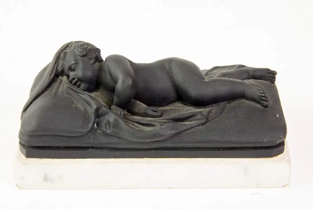 2 Figuren, 19. Jh., Wedgewood, Black Basalt, 2 schlafende Kinder, auf weißem Marmorsockel befestigt (geklebt), eine Figur mit stärkeren Beschädigungen und Restaurierungen, H: 6 cm, L: 14 cm. 0