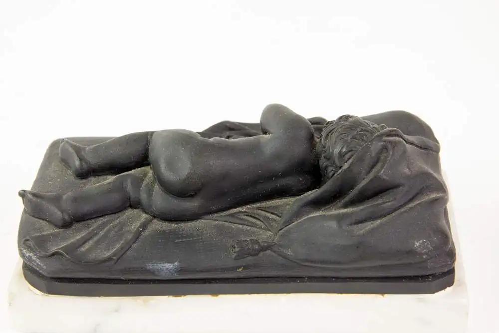 2 Figuren, 19. Jh., Wedgewood, Black Basalt, 2 schlafende Kinder, auf weißem Marmorsockel befestigt (geklebt), eine Figur mit stärkeren Beschädigungen und Restaurierungen, H: 6 cm, L: 14 cm. 1