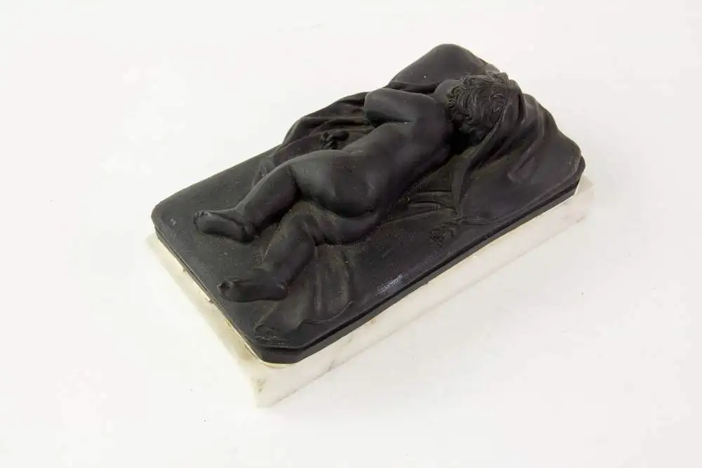 2 Figuren, 19. Jh., Wedgewood, Black Basalt, 2 schlafende Kinder, auf weißem Marmorsockel befestigt (geklebt), eine Figur mit stärkeren Beschädigungen und Restaurierungen, H: 6 cm, L: 14 cm. 8