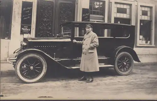 Un homme avec une voiture avant le magasin de tailleur, sans courir