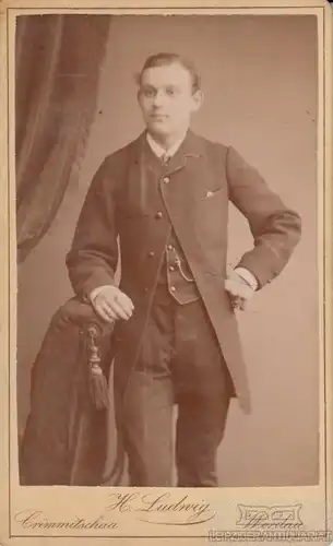 Portrait bürgerlicher junger Herr im Anzug an Sessel lehnend, Fotografie
