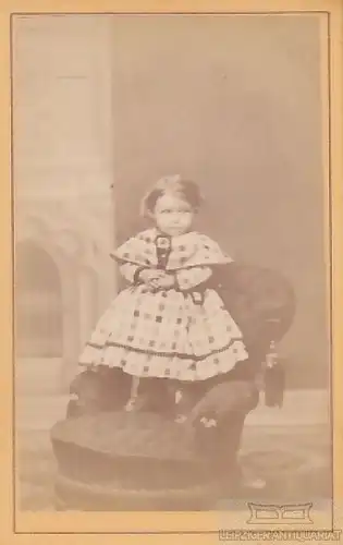 Portrait kleines Mädchen in kariertem Kleid auf Sessel stehend, Fotografie