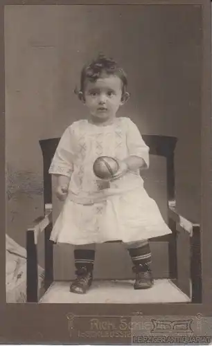 Portrait Kind auf Stuhl mit Ball, Fotografie. Fotobild, Atelier Rich. Schiewiek