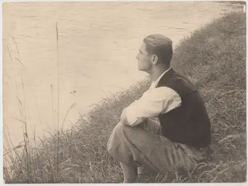 Fotografie Erich Henning (1907-1943) am Ufer sitzend, vor 1943, schwarzweiß