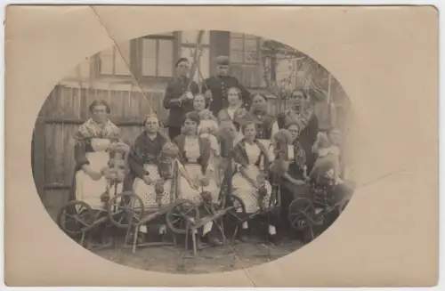 AK Gruppenfoto Spinnerei. Frauen in Tracht mit Spinnrad und 2 Männer in Uniform