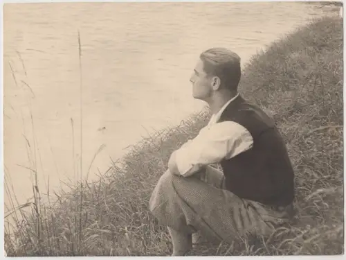 Fotografie Erich Henning (1907-1943) am Ufer sitzend, vor 1943, schwarzweiß