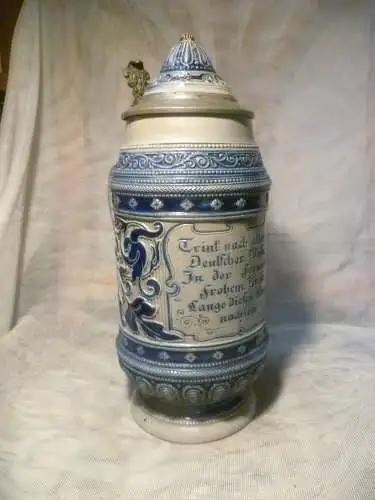 Westerwälder Steinzeugkrug ende 19 Jh., mit seitl. angesetztem Henkel, grauer Scherben mit blauer Bemalung, ornamentales Reliefdekor Formnummer 354 Gesamth. bis 29 cm Zinndeckel mit Keramikeinlage