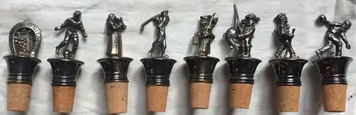 Acht versilberte Flaschenkorken mit verschiedenen Metallfiguren