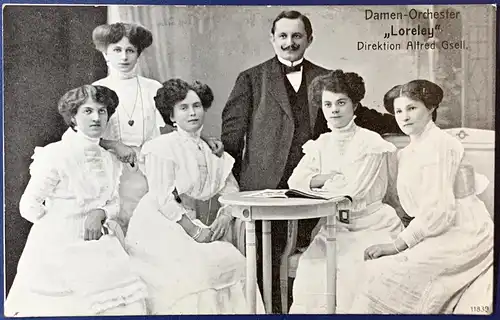 [Echtfotokarte schwarz/weiß] "Damen Orchester Loreley" Direktion Alfred Gsell, 1912, ungelaufen, auf der Rückseite leicht fleckig, ansonsten sehr gute Erhaltung. 