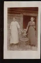 Zwei Frauen mit Blumen vor einem Bauernhaus. Foto