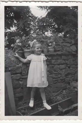 (F21307) Orig. Foto kleines Mädchen steht im Garten an einer Mauer 1930er