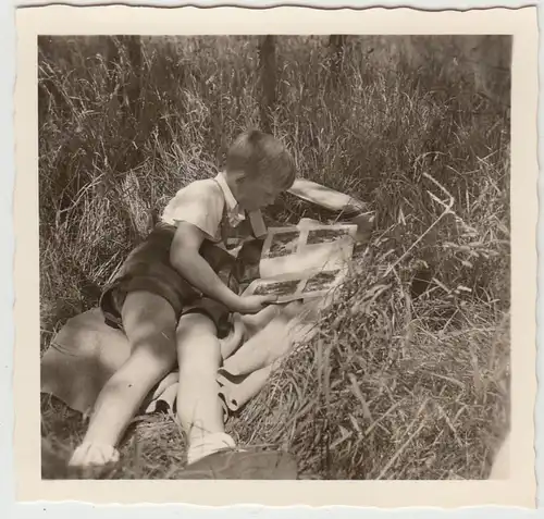 (F20128) Orig. Foto Junge liegt im Gras, schaut in Broschüre 1955