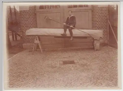 (F14191) Orig. Foto Mann sitzt auf selbstgebauten Sportboot vor Garage 1910