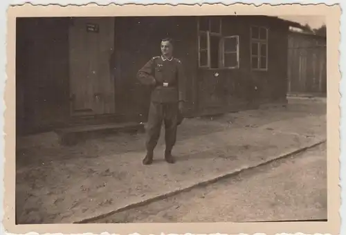 (F14083) Orig. Foto Wehrmacht-Soldat vor einer Baracke 1944