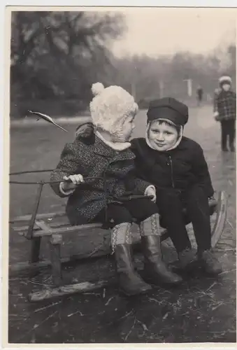 (F10777) Orig. Foto zwei kleine Kinder sitzen auf Schlitten ohne Schnee, DDR 196