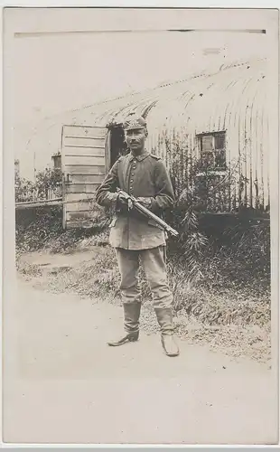 (80373) Foto AK 1.WK Soldat mit Pickelhaube und Gewehr vor Blech-Baracke